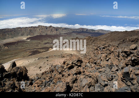 Overview of Las Canadas caldera from the 3700m summit of Mount Teide, the highest mountain in Europe, with old lava flows and pumice deposits, with clouds over the sea in the background, Tenerife, May. Stock Photo