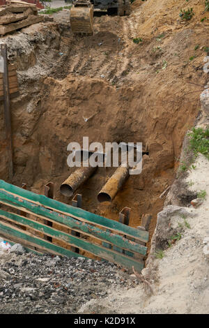 construction site yard with pipes sticking from the ground. city infrastructure repair plumbing in deep pit hole Stock Photo