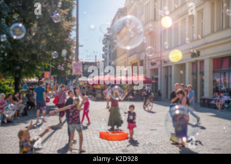 blurry street scene concept - Girl making soap bubbles on a sunny day Stock Photo