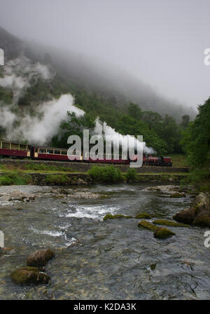A steam train enters Aberglaslyn Pass, alongside the river Glaslyn, near Beddgelert, Wales, UK June Stock Photo