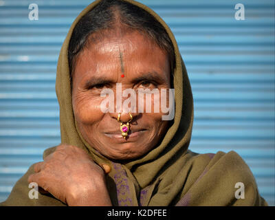 Indian Adivasi woman (Desia Kondh tribe, Kuvi Kondh tribe) with gold-and-gemstone nose jewellery and tattoo on her forehead smiles for the camera. Stock Photo