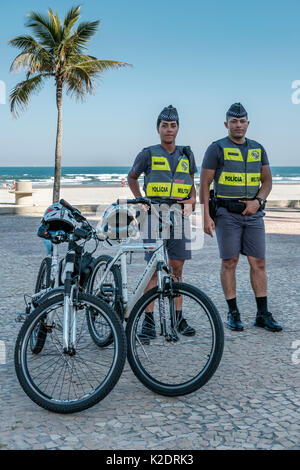 Male and female Brazilian military police officers standing by their bicycles at the beach Praia Grande, State of Sao Paulo, Brazil. Stock Photo