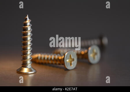 Extreme closeup of few brass screws on dark background Stock Photo