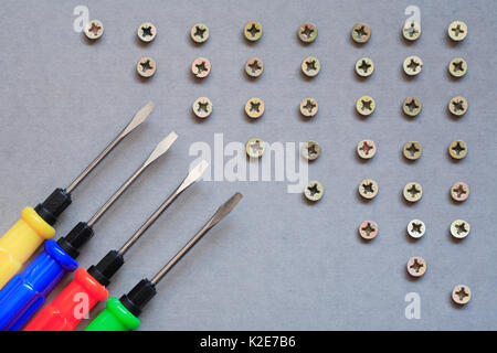 Industrial concept. Set of color screwdrivers near lot of screws Stock Photo