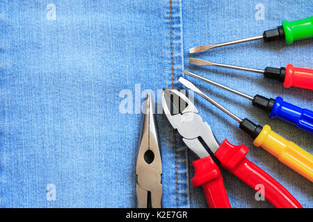 Set of color various work tools on blue denim surface Stock Photo
