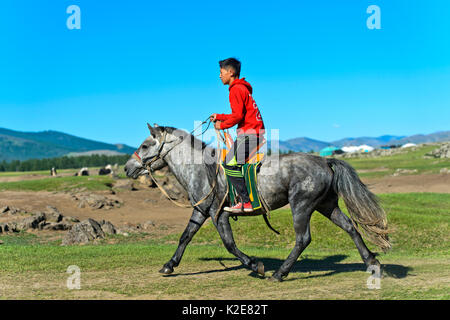 Boy rides on a horse through the steppe, Orchon Valley, Khangai Nuruu National Park, Övörkhangai Aimag, Mongolia Stock Photo