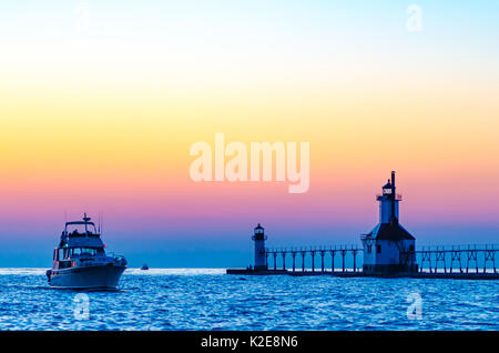 A boat on Lake Michigan passes the lighthouse at St. Joseph, Michigan, as the boat enters the St. Joseph River Stock Photo