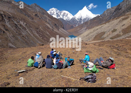 Hikers take a tea break on the asent to Bhonte La Pass (4,380m/16,00ft) the high point of Jhomolhari Trek.  Bhutan, October 2014. Model released. Stock Photo
