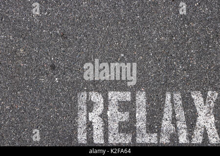 Road asphalt texture. Bitumen surface structure with painted relax word. Stock Photo