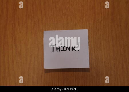 Hand written note with the term Think on it stuck to the wood surface of a notice board in landscape format a clear background and copy space Stock Photo