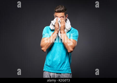 A handsome young sportsman feeling tired and wiping his face with a towel Stock Photo