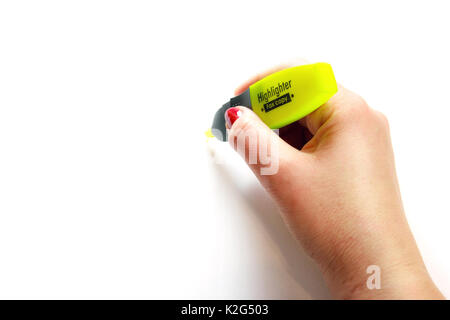 Woman hand with red nail polish with yellow highlighter on white background Stock Photo