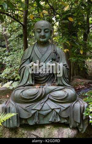 Tokyo, Japan -  Buddha statue with Japanese coins in the garden of the Nezu museum Stock Photo