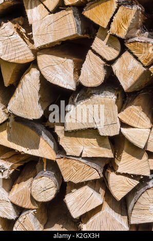 Splitted, dried and stacked firewood, vertical front view. Stack of weathered, dry wood, a source of energy. Photo. Stock Photo