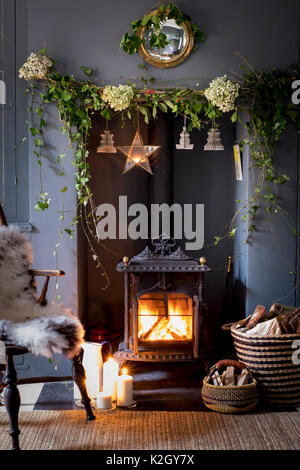 Cosy Christmas fireplace with wood burning stove and holly and ivy decorations Stock Photo