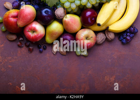 Ripe organic fruits on rustic background with copyspace. Bananas,pear,plum,peach, apples, red and white grapes Stock Photo