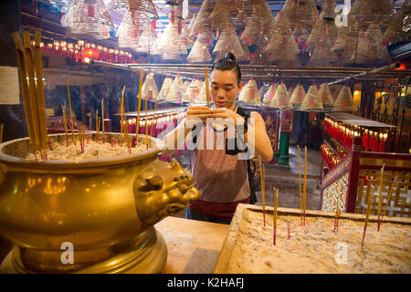 A young man prays at the Man Mo temple, Hong Kong Island Stock Photo