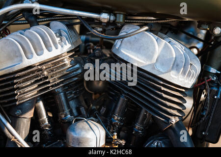 Details of an engine of a vintage motorcycle. White color cilinder ratiators, cast metal tubes, wires and joints. Stock Photo