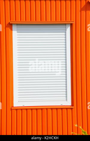 Window with closed shutters on an orange Container Stock Photo