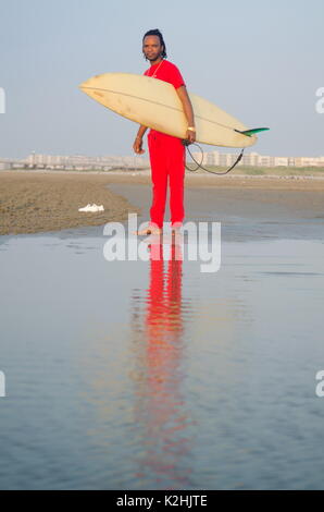 Man holding a surfboard on the beach with calm seaside Stock Photo