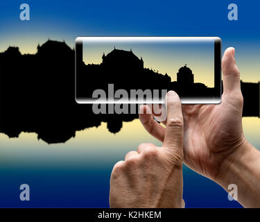 Two hands holding a mobile Smartphone and take a picture of a city silhouette Stock Photo