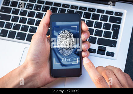 Fingerprint scanning on smartphone screen with finger touching biometric digital scanner, identity verification, cybersecurity access control Stock Photo