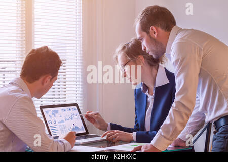 Team of finance people discussing charts and key performance indicator (KPI) on computer screen with business intelligence (BI) in meeting room, corpo Stock Photo