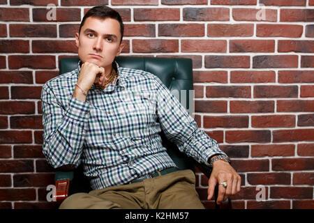Picture of business man sitting in leather chair on brick wall background Stock Photo