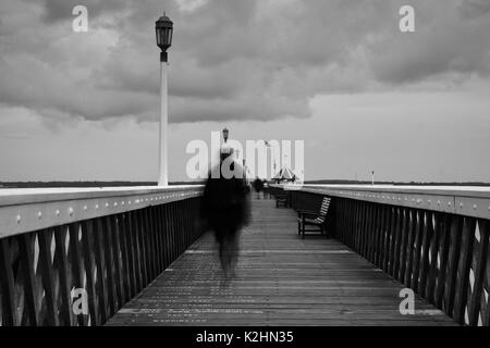 A mystery figure on the all wooden pier of Yarmouth based on the Isle Of Wight Stock Photo
