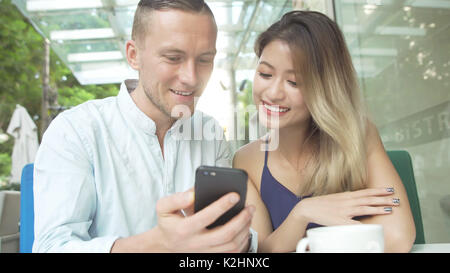 Young multicultural couple using smartphone to manage tasks and ...