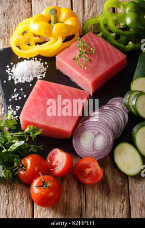 Raw fillet of tuna with vegetables and herbs close-up on the table. vertical Stock Photo
