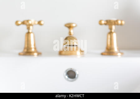 Brass basin taps in white bathroom Stock Photo