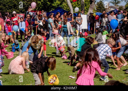 Multiracial children carrying baskets swarm across the lawn of a park in Costa Mesa, CA, searching for scattered Easter prizes. Stock Photo