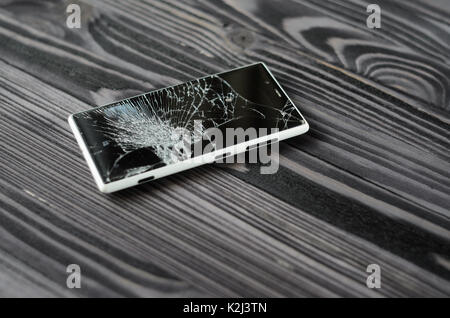 Smartphone with broken screen on dark wooden background Stock Photo