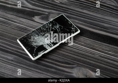 Smartphone with broken screen on dark wooden background Stock Photo