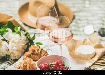 French style romantic summer picnic setting. Flat-lay of glasses of rose wine with ice, fresh strawberries, croissants, brie cheese, straw hat, sungla Stock Photo