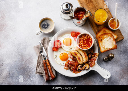 English breakfast in white pan with fried eggs, sausages, bacon, beans, toasts, orange fresh and coffee on white background copy space Stock Photo