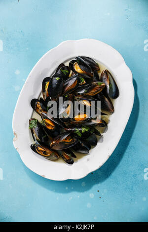 Mussels on white plate on blue background Stock Photo
