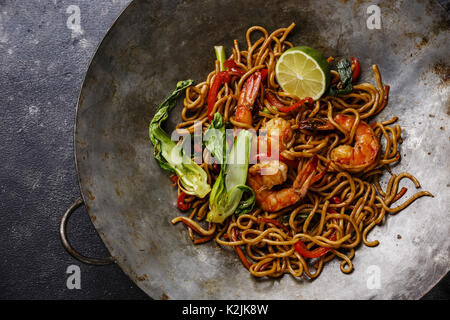 Udon noodles stir-fried with Tiger shrimps and vegetable in wok cooking pan close-up Stock Photo