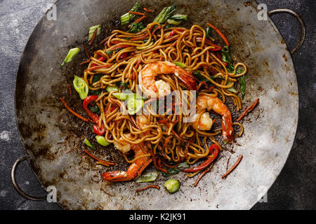 Udon noodles stir-fried with Tiger shrimps and vegetable in wok cooking pan close-up Stock Photo