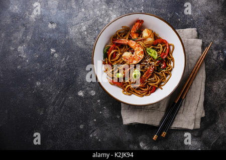 Udon noodles stir-fried with Tiger shrimps and vegetable in bowl on dark background copy space Stock Photo