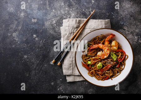 Udon noodles stir-fried with Tiger shrimps and vegetable in bowl on dark background copy space Stock Photo