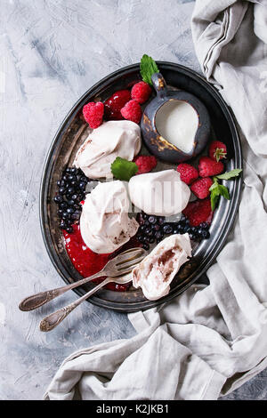Traditional summer dessert Eton Mess. Meringue, jug of cream, berry jam, fresh blueberries, raspberries on vintage tray, decorated with mint leaves ov Stock Photo