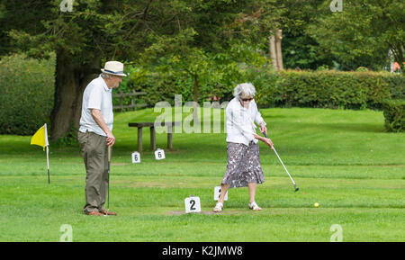 Elderly couple playing putting on a small putting course in Summer in the UK. Active pensioners. Stock Photo