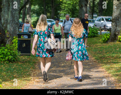 Pair of young women dressed in identical Summer dresses walking in Summer. 2 of a kind concept. Twins. Note: The women may or may not be related. Stock Photo