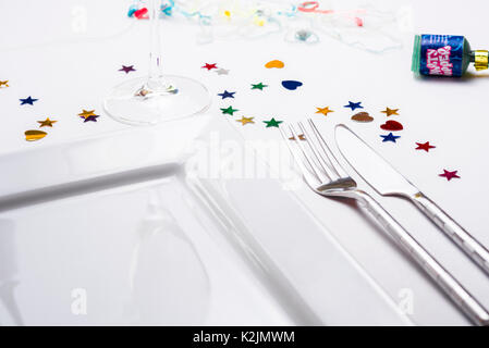 Single place table setting, knife fork plate, with decoration confetti. Stock Photo