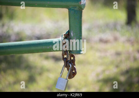 Open gate with a rusted chain and lock hanging from it Stock Photo