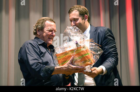 Former Chancellor Gerhard Schroder (L) receiving a gift from the SPD's top candidate in the district, Lars Klingbeil, after an SPD campaign event in the Diakonie Hospital in Rotenburg, Germany, 30 August 2017. Photo: Carmen Jaspersen/dpa Stock Photo