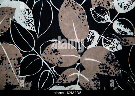 Knitwear fabric with floral abstract pattern of black, gray and white silhouettes of leaves. Stock Photo