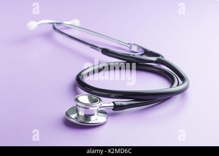 Black medical stethoscope on purple background. Stethoscope for listening to the heart. Stock Photo
